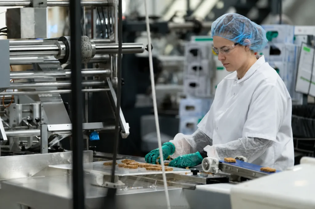 Food production worker operating a flow-wrapper packaging line in a co-packing facility